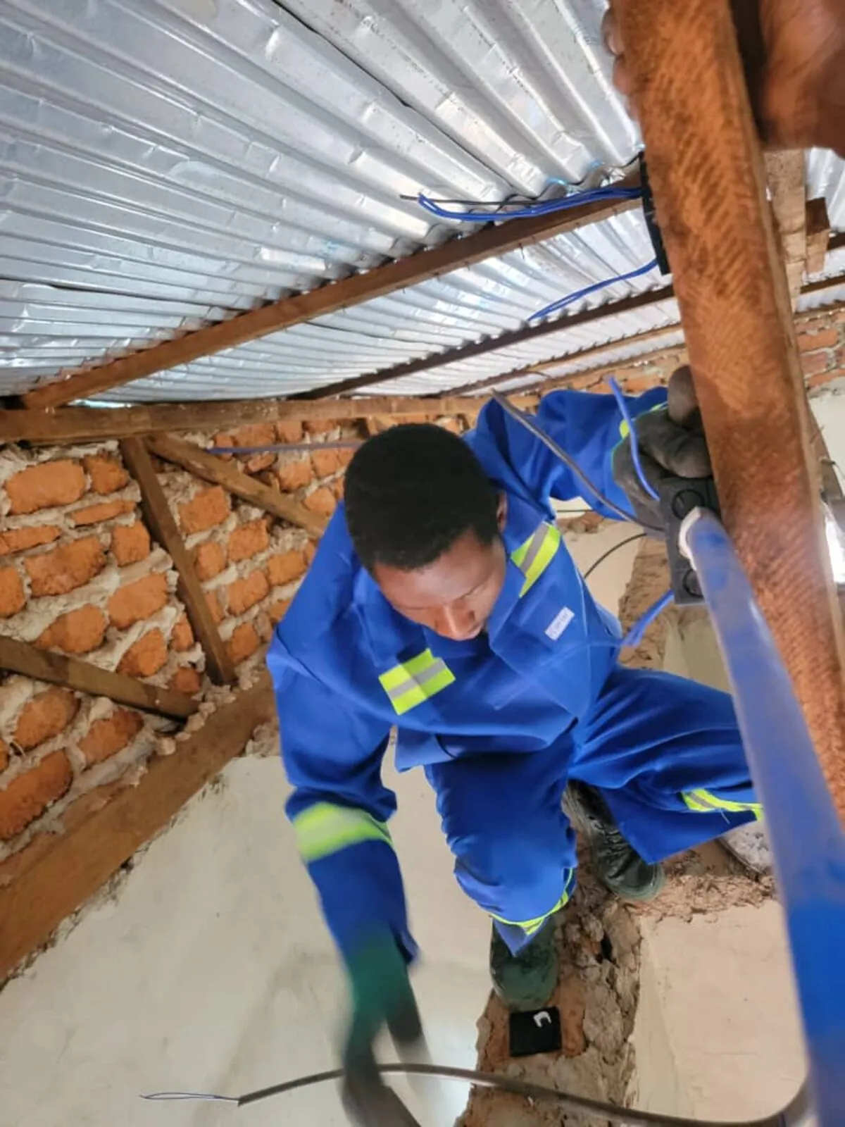 Technicien KMM Service passant des câbles en toiture